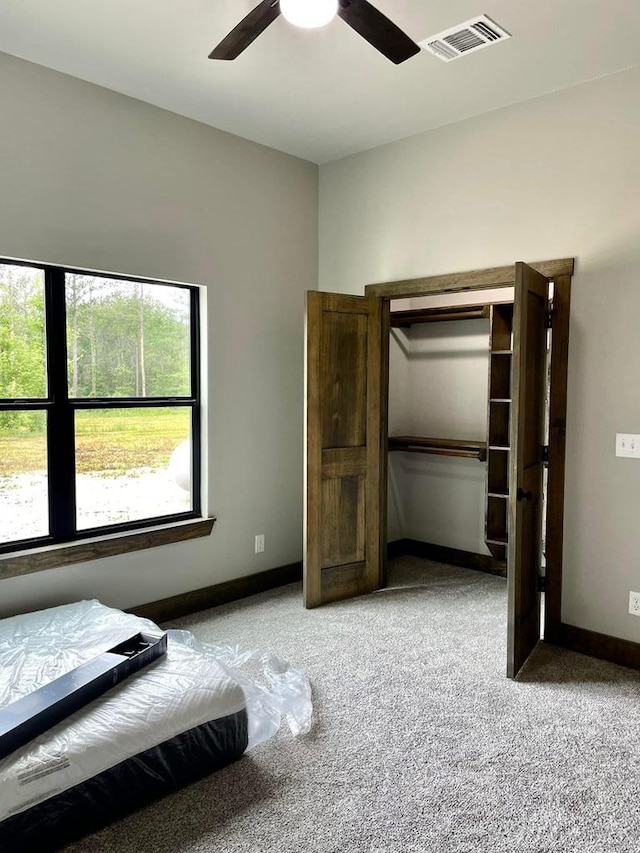 carpeted bedroom featuring baseboards, a ceiling fan, and visible vents