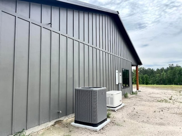 view of side of home featuring a forest view, central AC unit, and board and batten siding