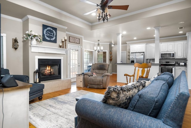 454 Bobwhite Dr, Lufkin, TX 74904 - living area with light wood-type flooring, ceiling fan, ornate columns, a chandelier, and a lit fireplace