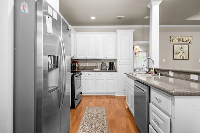 454 Bobwhite Dr, Lufkin, TX 74904 - kitchen with stainless steel appliances, white cabinets, crown molding, ornate columns, and light wood-style flooring