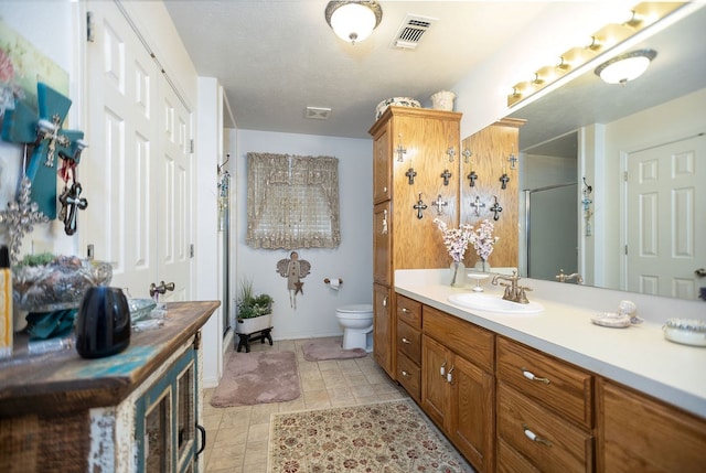 full bathroom with toilet, vanity, visible vents, and a stall shower