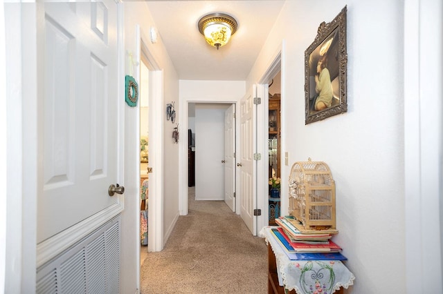 corridor featuring carpet floors, visible vents, and baseboards