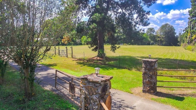 view of home's community featuring a rural view, a lawn, and fence