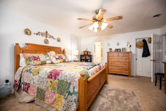 carpeted bedroom featuring a ceiling fan, visible vents, and connected bathroom