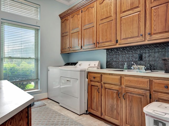 washroom featuring sink, cabinets, washing machine and dryer, crown molding, and light tile patterned flooring