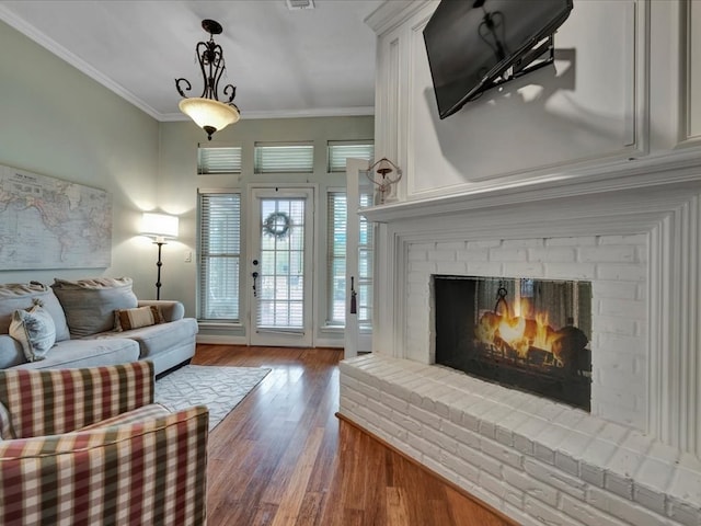 living area featuring hardwood / wood-style flooring, a brick fireplace, and ornamental molding