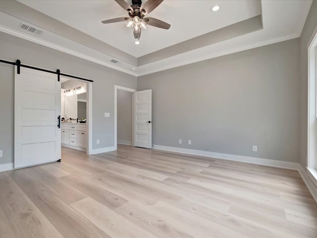 234 Lancewood Dr, Lufkin, TX 75904 - unfurnished bedroom with a barn door, a tray ceiling, light wood-style flooring, crown molding, and recessed lighting