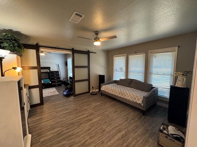270 Lakeshore Dr, Brookeland, TX 75931 - bedroom with wood finished floors, a textured ceiling, access to outside, a ceiling fan, and a barn door