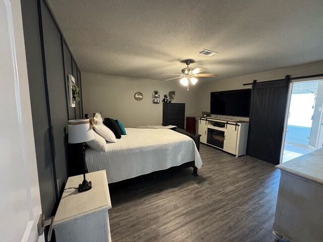 270 Lakeshore Dr, Brookeland, TX 75931 - bedroom with wood finished floors, a textured ceiling, access to outside, a ceiling fan, and a barn door