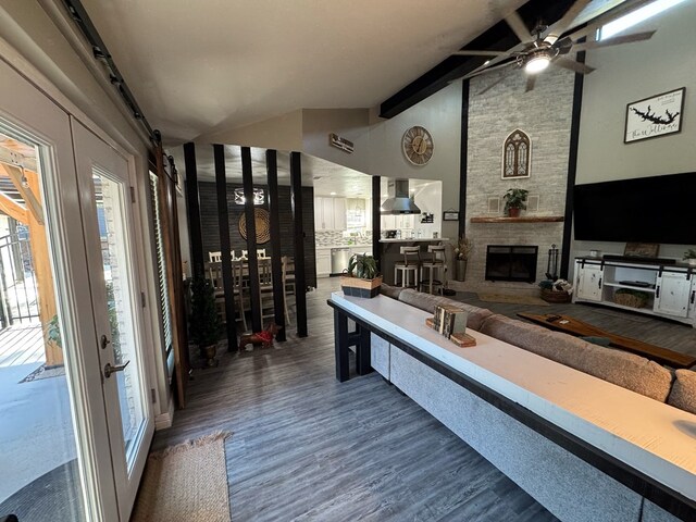270 Lakeshore Dr, Brookeland, TX 75931 - interior space with a ceiling fan, wood finished floors, a stone fireplace, beamed ceiling, and high vaulted ceiling
