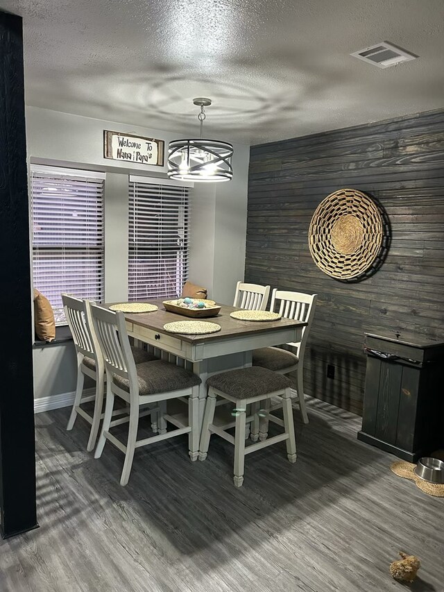 270 Lakeshore Dr, Brookeland, TX 75931 - dining space with wood finished floors, a textured ceiling, and wood walls