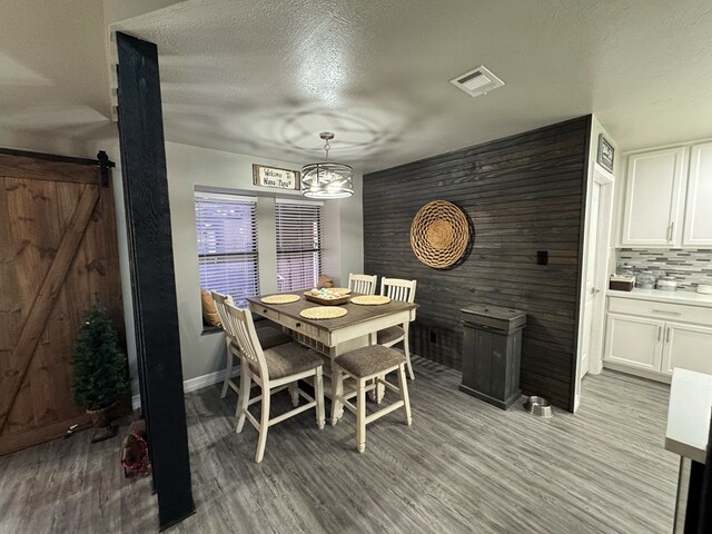 270 Lakeshore Dr, Brookeland, TX 75931 - dining room featuring light wood finished floors, a textured ceiling, a chandelier, and a barn door