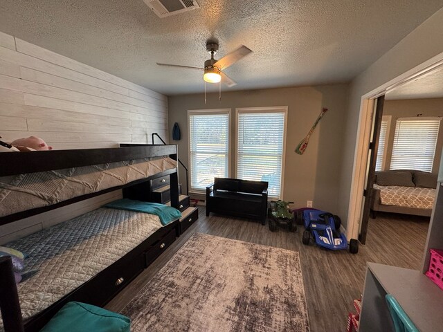 270 Lakeshore Dr, Brookeland, TX 75931 - bedroom with wood finished floors, wooden walls, a textured ceiling, and a ceiling fan