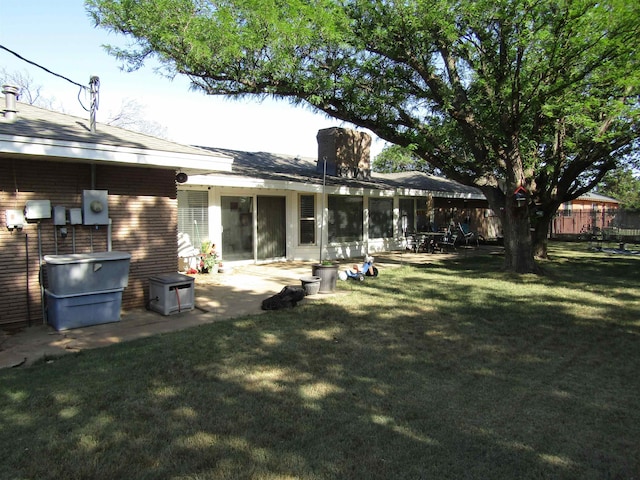 rear view of house featuring a lawn and a patio area