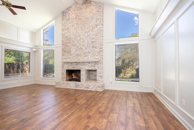 unfurnished living room featuring hardwood / wood-style flooring, ceiling fan, a large fireplace, and high vaulted ceiling