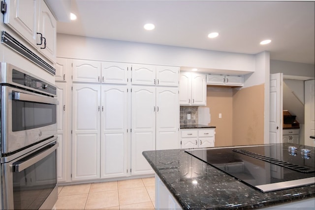 kitchen with dark stone countertops, white cabinetry, black electric cooktop, and stainless steel double oven