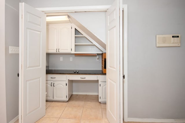 interior space featuring white cabinetry, built in desk, and light tile patterned floors