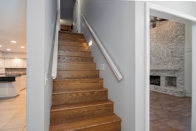 stairway with hardwood / wood-style floors and a large fireplace