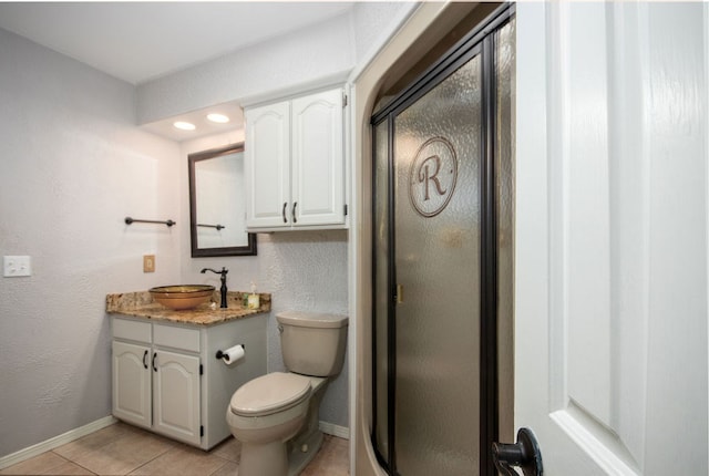 bathroom featuring toilet, vanity, tile patterned floors, and a shower with door