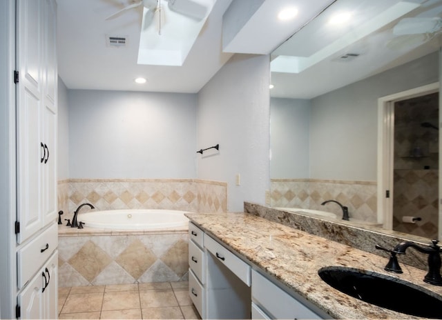 bathroom featuring tile patterned flooring, vanity, ceiling fan, and tiled tub