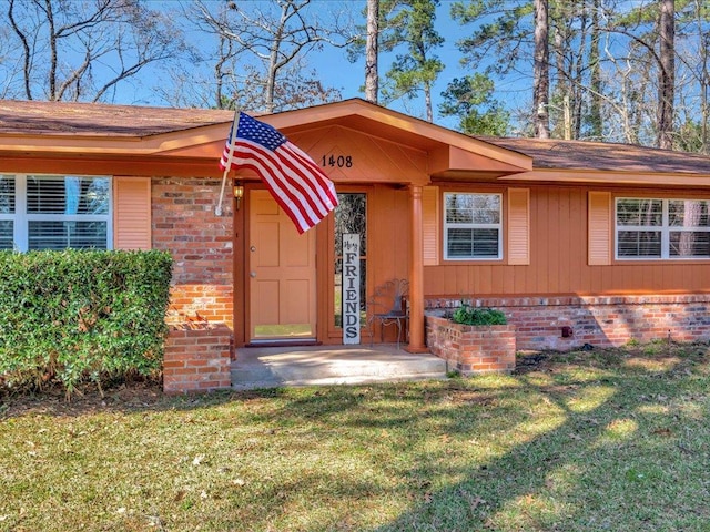 doorway to property with brick siding and a yard