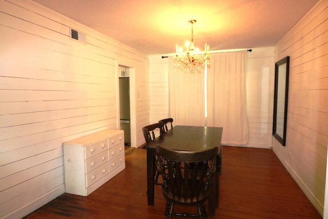 dining area with dark hardwood / wood-style flooring, wooden walls, and a chandelier