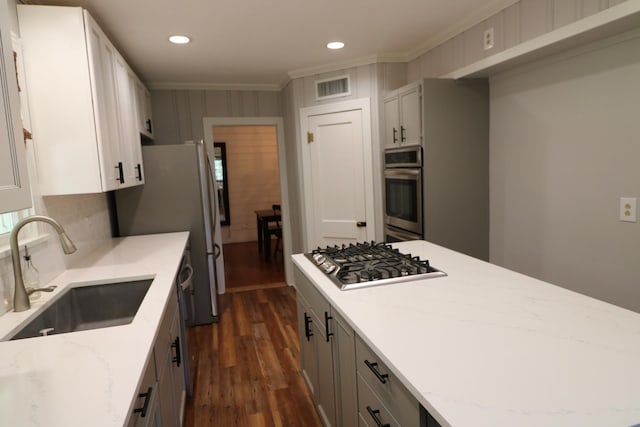 kitchen with crown molding, sink, light stone countertops, appliances with stainless steel finishes, and dark hardwood / wood-style flooring