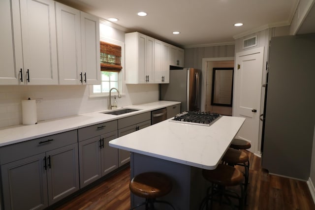 kitchen featuring a kitchen breakfast bar, ornamental molding, stainless steel appliances, sink, and a center island