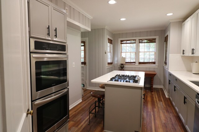 kitchen with white cabinetry, a center island, stainless steel appliances, a breakfast bar, and ornamental molding