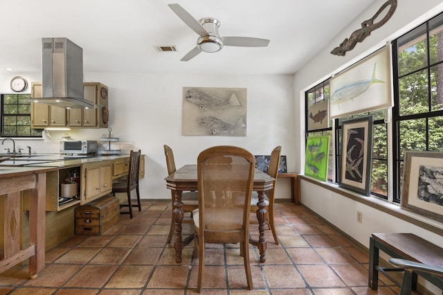 tiled dining room featuring ceiling fan and sink