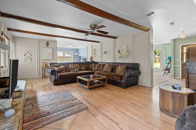 living room featuring ceiling fan, light hardwood / wood-style flooring, and beamed ceiling