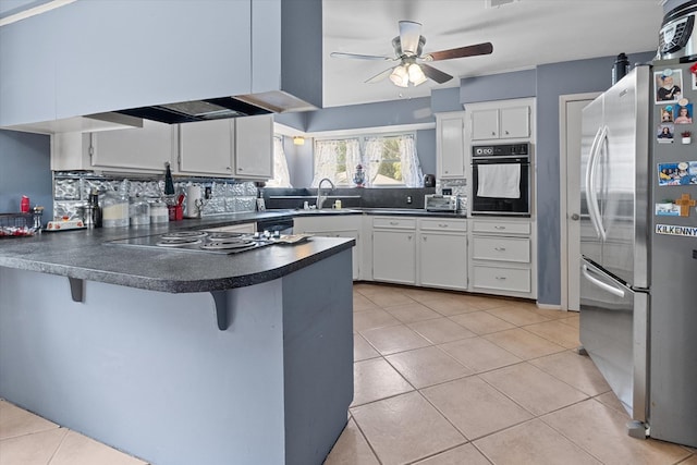 kitchen with oven, white cabinetry, kitchen peninsula, and stainless steel refrigerator