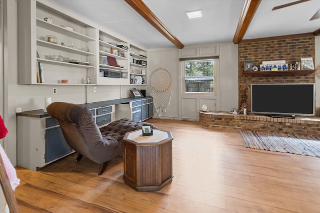 living room featuring ceiling fan, light hardwood / wood-style flooring, and beamed ceiling