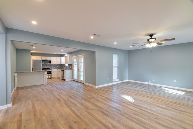 unfurnished living room with light wood finished floors, visible vents, baseboards, and ceiling fan