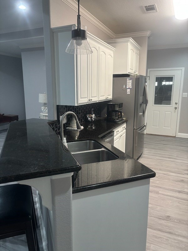 138 Breezeway Dr, Brookeland, TX 75931 - kitchen featuring a sink, a peninsula, dark stone counters, visible vents, and white cabinetry