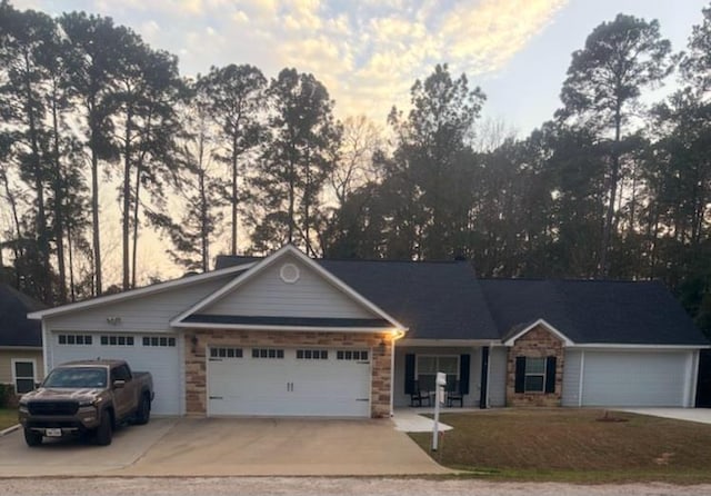 single story home featuring an attached garage, concrete driveway, and stone siding