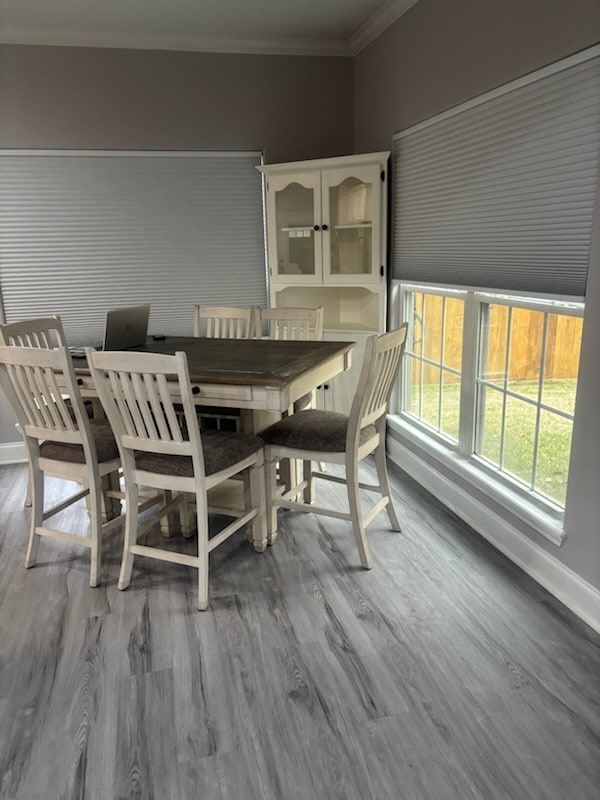 dining room featuring crown molding, baseboards, and wood finished floors