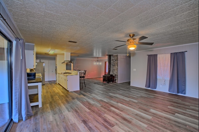 interior space with a wood stove, visible vents, ceiling fan, and wood finished floors