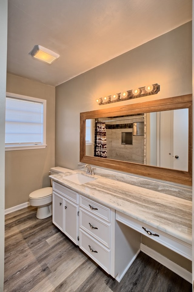 bathroom featuring baseboards, toilet, a shower with curtain, wood finished floors, and vanity