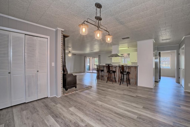 kitchen with a breakfast bar, crown molding, island exhaust hood, freestanding refrigerator, and wood finished floors