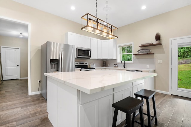 155 Sweetbriar Ct, Brookeland, TX 75931 - kitchen with appliances with stainless steel finishes, open shelves, a kitchen island, a kitchen bar, and white cabinets