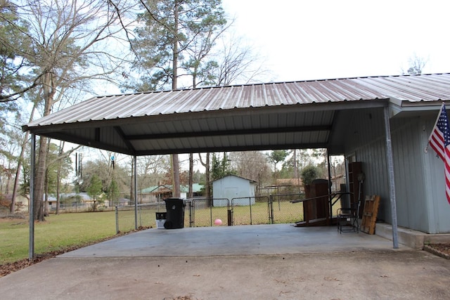 view of car parking with a carport, a gate, fence, and a storage unit