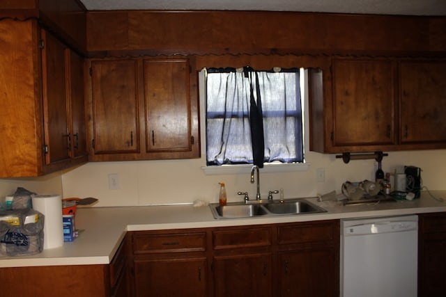 kitchen featuring light countertops, white dishwasher, and a sink