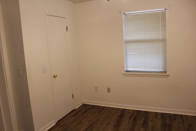 spare room featuring baseboards and dark wood-style flooring