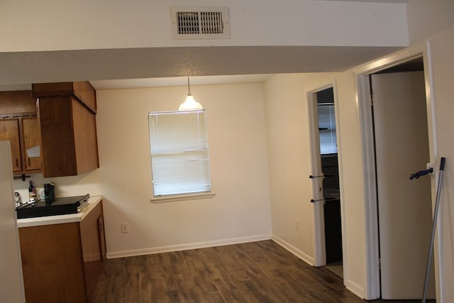 kitchen with brown cabinetry, dark wood-style flooring, visible vents, and baseboards