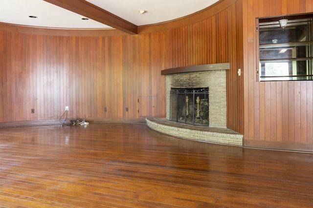 unfurnished living room featuring wood walls, beamed ceiling, and wood-type flooring