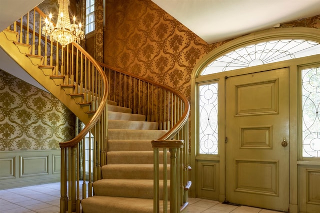 foyer entrance with plenty of natural light, light tile patterned flooring, and an inviting chandelier