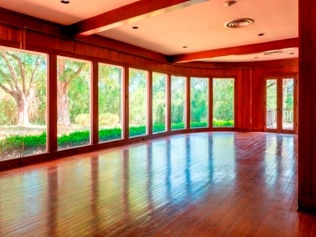 unfurnished sunroom featuring beam ceiling and plenty of natural light