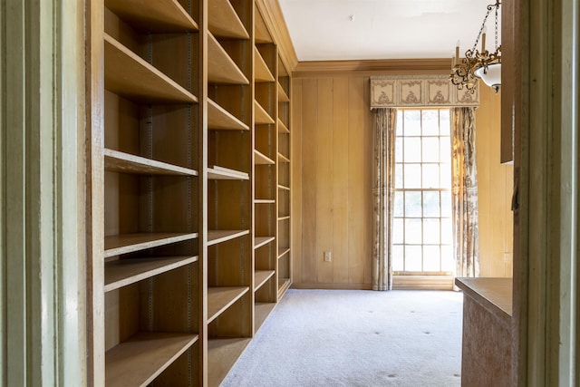 miscellaneous room featuring carpet flooring, a chandelier, ornamental molding, and wood walls