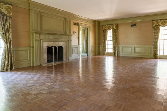 unfurnished living room featuring parquet floors, a fireplace, and ornamental molding